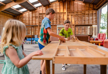 Niños juegan a un juego de mesa dentro de una gran tienda safari en CharmeCamping De Regge-Vallei, Países Bajos.