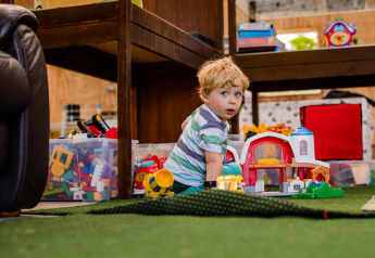 Jonge jongen speelt met speelgoed op de vloer in een safaritent, omringd door kleurrijke opbergdozen.