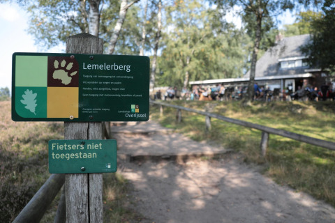 Bord bij Lemelerberg glamping dat fietsers weert en alleen wandelaars in het natuurgebied toelaat.