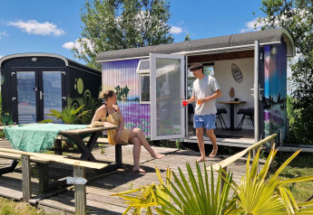 Due persone si rilassano davanti a una tiny house colorata chiamata Tiny wagon a Marina Parcs Almere, Paesi Bassi.