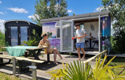 Dos personas se relajan frente a una colorida tiny house llamada Tiny wagon en Marina Parcs Almere, Países Bajos.