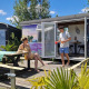 Due persone si rilassano davanti a una tiny house colorata chiamata Tiny wagon a Marina Parcs Almere, Paesi Bassi.