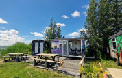 Vue extérieure du Tiny Wagon à Marina Parcs Almere, Pays-Bas, avec tables pique-nique et vue sur le lac.