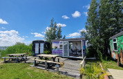 Buitenaanzicht van Tiny Wagon bij Marina Parcs Almere, Nederland, met picknicktafels en uitzicht op het meer.