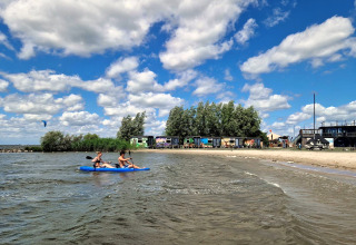 Twee mensen kajakken voor Tiny Wagon bij Marina Parcs Almere, Nederland, op een zonnige dag.