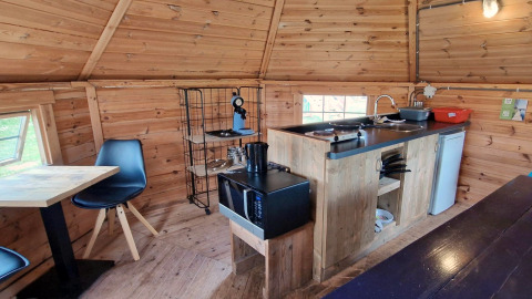 Kleine keuken in de Tiny Wagon met houten wanden, tafel, stoelen en apparatuur bij Marina Parcs Almere.