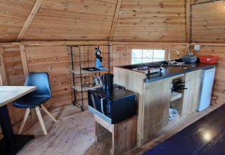 Knusse kitchenette in de Tiny Wagon met houten wanden, eettafel en toestellen bij Marina Parcs Almere.