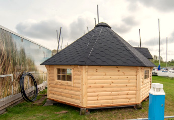 Lille træhus med sort tag, Tiny Wagon ved Marina Parcs Almere, med både og havn i Holland.