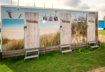 Udendørs badeværelsesfaciliteter ved Tiny Wagon, Marina Parcs Almere, med strandtema i Holland.