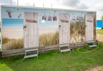 Outdoor bathrooms at Tiny Wagon, Marina Parcs Almere, Netherlands, featuring beach-themed decoration.