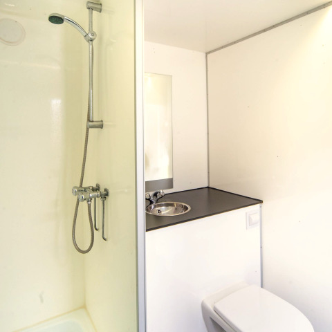 Moderne, compacte badkamer met douche, wastafel en toilet in het Tiny Wagon bij Marina Parcs Almere.