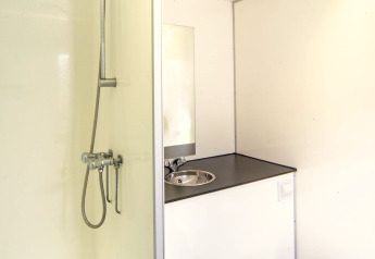 Bagno compatto e moderno con doccia, lavandino e WC nel Tiny Wagon al Marina Parcs Almere, Paesi Bassi.
