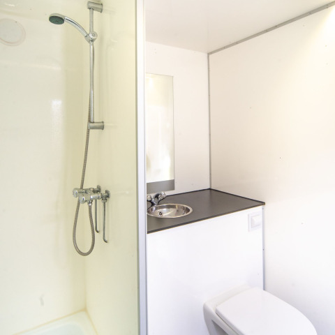 Bagno compatto e moderno con doccia, lavandino e WC nel Tiny Wagon al Marina Parcs Almere, Paesi Bassi.