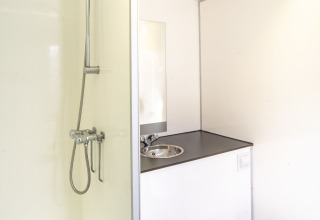 Baño compacto moderno con ducha, lavabo y aseo en el Tiny Wagon de Marina Parcs Almere, Países Bajos.