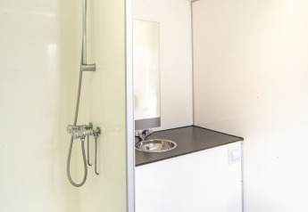 Bagno compatto e moderno con doccia, lavandino e WC nel Tiny Wagon al Marina Parcs Almere, Paesi Bassi.