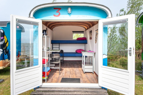 Tiny wagon con puertas abiertas en Marina Parcs Almere, Países Bajos. Interior compacto junto al lago.