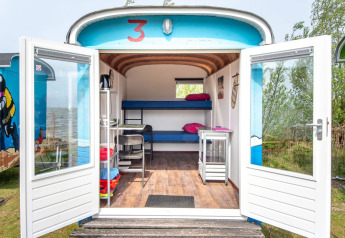 Tiny wagon con puertas abiertas en Marina Parcs Almere, Países Bajos. Interior compacto junto al lago.