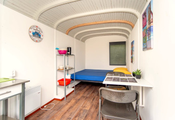 Indvendig udsigt af Tiny Wagon ved Marina Parcs Almere, Nederlandene, med seng, bord og hylder.