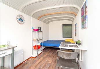 Binnenaanzicht van de Tiny Wagon bij Marina Parcs Almere, Nederland, met bed, tafel en planken.