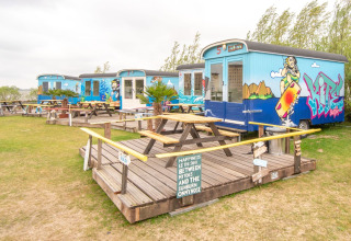 Pequeñas casas rodantes coloridas con arte de graffiti y mesas de picnic en Marina Parcs Almere, Países Bajos.