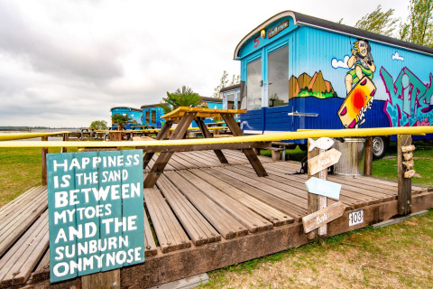 Tiny house colorata al Marina Parcs Almere, Paesi Bassi, decorata con graffiti e tavoli da picnic in legno.