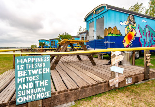 Tiny house colorida en Marina Parcs Almere, Países Bajos, con arte urbano, mesas y ambiente natural.