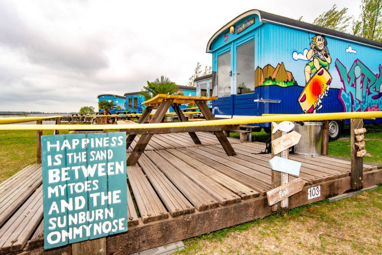Buntes Tiny House im Marina Parcs Almere, Niederlande, mit Graffiti, Picknicktisch und naturnaher Umgebung.
