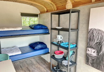 Interiør af Tiny Wagon ved Marina Parcs Almere med køjesenge, reol og køkkenudstyr i Holland.