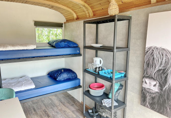 Interno della Tiny Wagon a Marina Parcs Almere con letti a castello, scaffale e stoviglie nei Paesi Bassi.