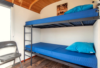 Interno luminoso del Tiny Wagon a Marina Parcs Almere, Paesi Bassi, con letto a castello e biancheria blu.