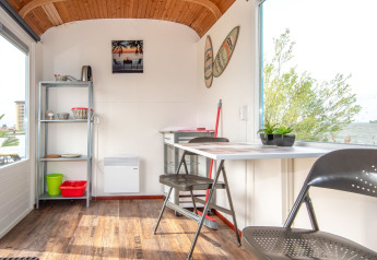 Indretning af Tiny Wagon ved Marina Parcs Almere i Nederlandene med udsigt over vandet og en hyggelig spiseplads.
