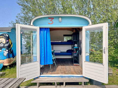 Tiny wagon bij Marina Parcs Almere in Nederland met open deuren, stapelbedden en kleurrijke decoratie.