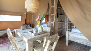 Interior view of a cozy safari tent, Safari lodge, featuring rustic wood furniture at Marina Parcs Almere, Netherlands.