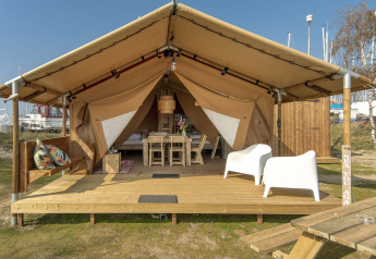 Tienda safari en Marina Parcs Almere, Países Bajos, con terraza de madera, sillas y decoración acogedora.