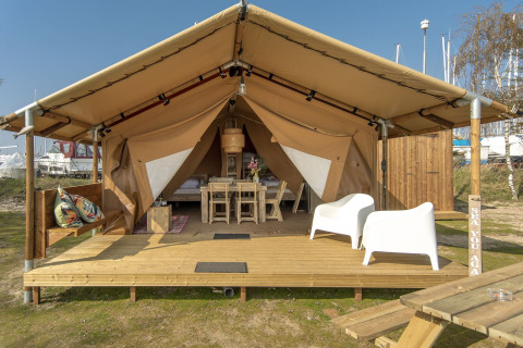 Tenda safari al Marina Parcs Almere nei Paesi Bassi con terrazza in legno, sedie e arredo accogliente.