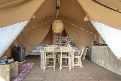 Vue intérieure d'une tente safari lodge avec des meubles en bois rustiques à Marina Parcs Almere, Pays-Bas.