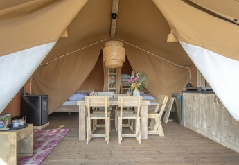 Vue intérieure d'une tente safari lodge avec des meubles en bois rustiques à Marina Parcs Almere, Pays-Bas.
