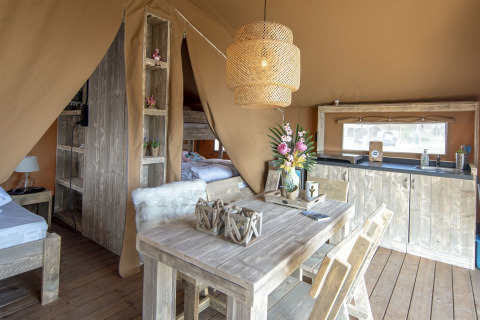 Intérieur d'une tente Safari Lodge au Marina Parcs Almere, Pays-Bas, avec meubles en bois et décoration chaleureuse.