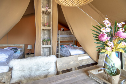 Interieur van Safari Lodge tent bij Marina Parcs Almere met stapelbedden, bloemen en knusse inrichting.