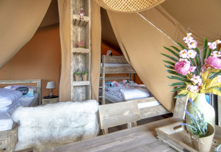Interieur van de Safari Lodge tent bij Marina Parcs Almere met stapelbedden, bloemen en een gezellige sfeer.