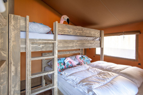 Intérieur chaleureux d'une chambre sous tente safari au Marina Parcs Almere avec lits superposés et simples.