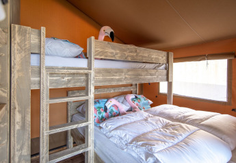Intérieur chaleureux d'une chambre sous tente safari au Marina Parcs Almere avec lits superposés et simples.