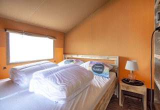 Binnenzicht van de Safari lodge tent bij Marina Parcs Almere, Nederland, met bed en nachtkastje.