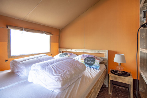 Foto interior de la tienda Safari lodge en Marina Parcs Almere, Países Bajos, con cama y mesita de noche.