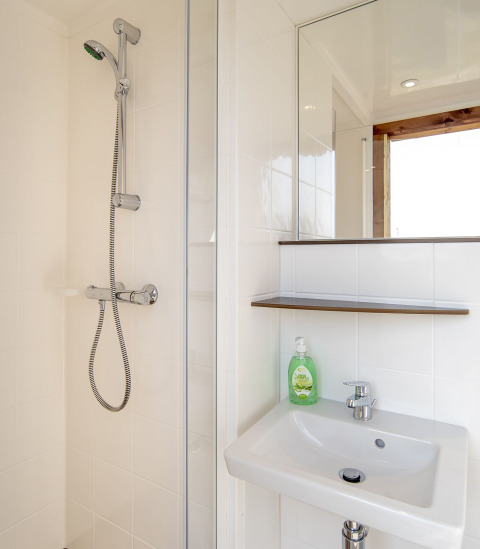 Salle de bain moderne dans la Safari lodge à Marina Parcs Almere avec douche, lavabo, miroir et savon.