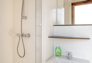 Moderne badkamer in Safari lodge bij Marina Parcs Almere met douche, wasbak, spiegel en handzeep.