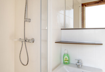Salle de bain moderne dans la Safari lodge à Marina Parcs Almere avec douche, lavabo, miroir et savon.