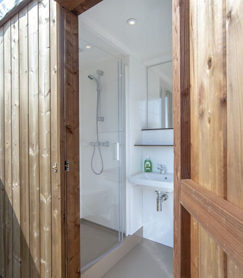 Salle de bains moderne avec douche et lavabo dans une tente safari à Marina Parcs Almere, Pays-Bas.