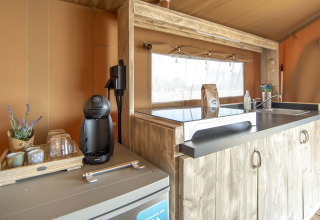 Køkkenområde i en safarilodge med kaffemaskine, vask og træelementer hos Marina Parcs Almere, Holland.
