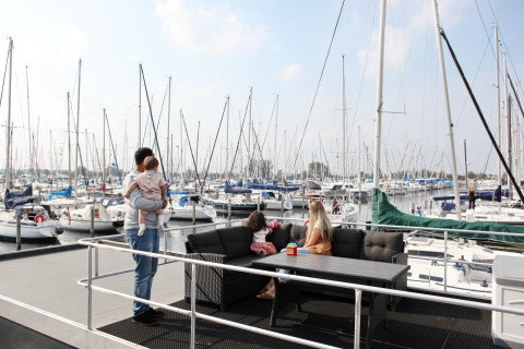 Family relaxing on the House boat 4-Almere at Marina Parcs Almere in the Netherlands, overlooking sailboats.